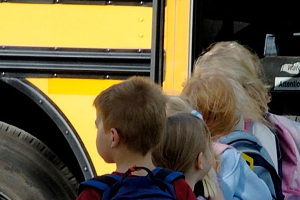 Administrative Support image: children lined up to get on a school bus